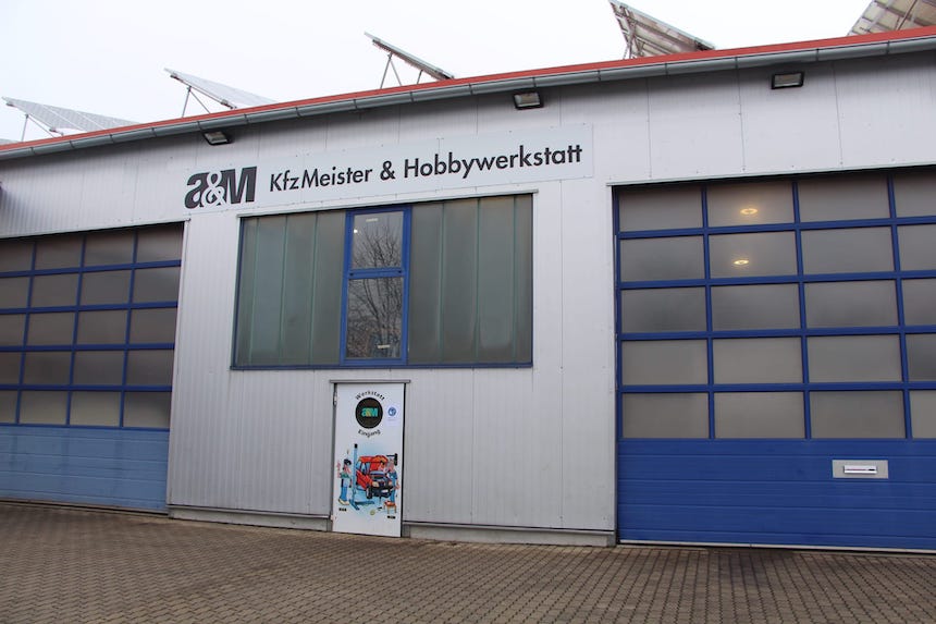 AM KFZ Meisterwerkstatt Schriftzug an einm Gebäude über blauen Toren